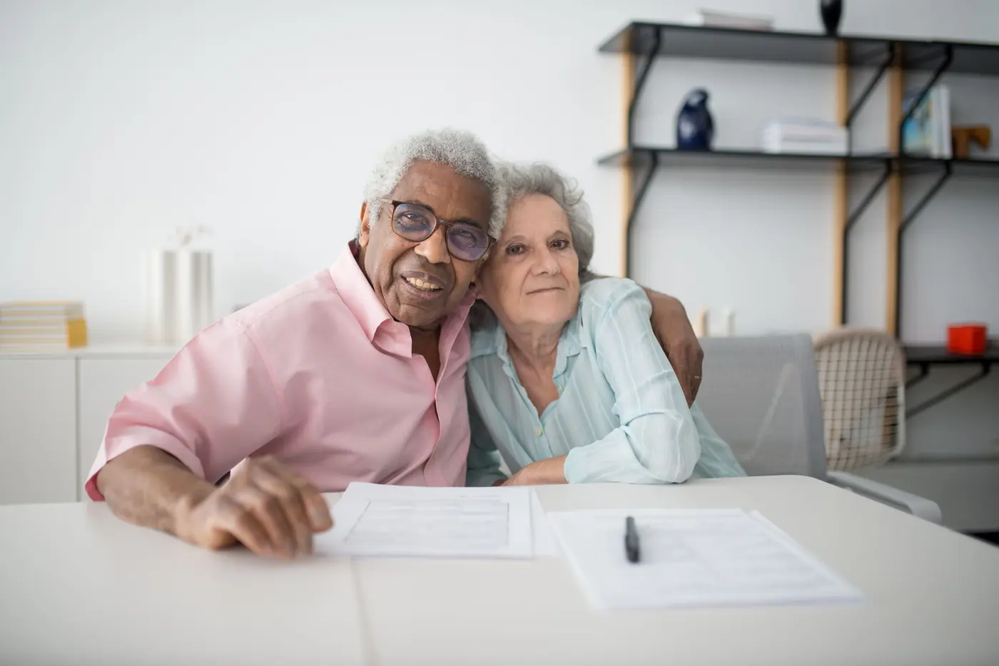 An older couple smiling together at their table at home